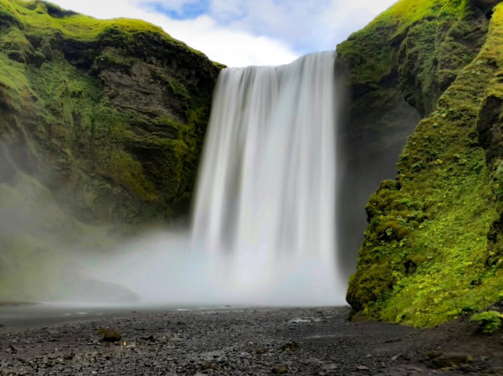 Breathtaking view of Skógafoss waterfall cascading amidst lush greenery in Iceland.